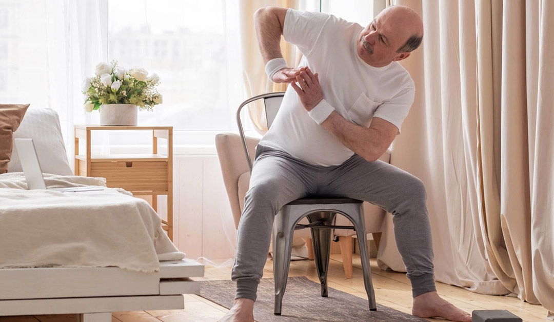 Elderly man sitting in a chair performing exercises